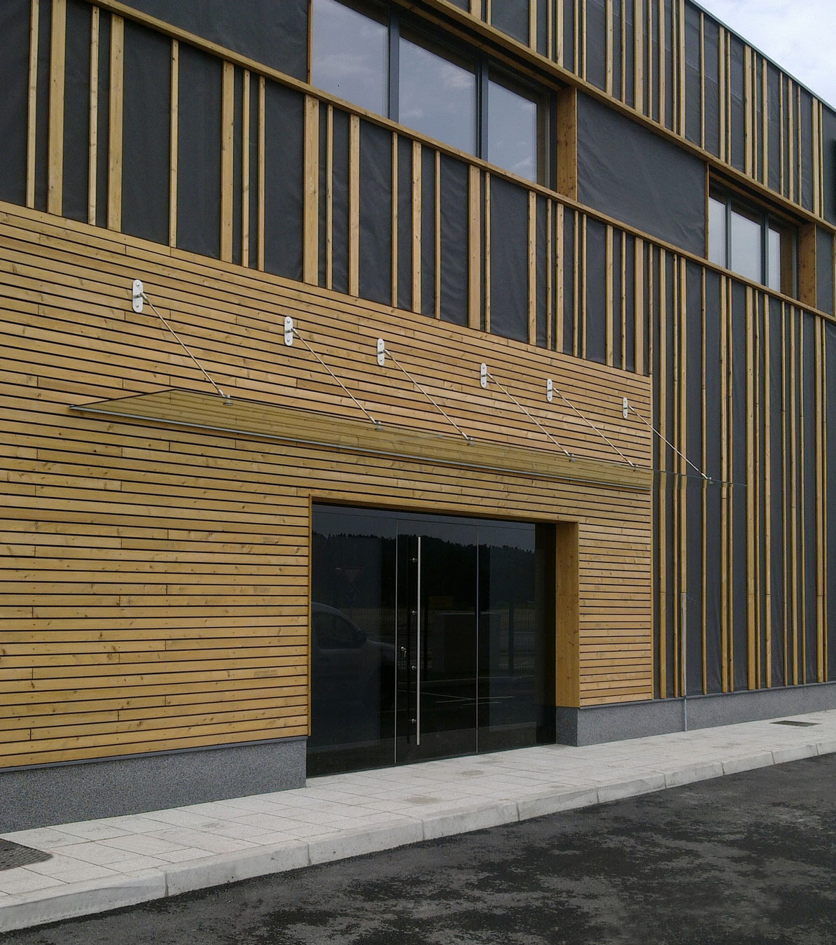 Haustür aus Aluminium an einem Gebäude mit Holzfassade