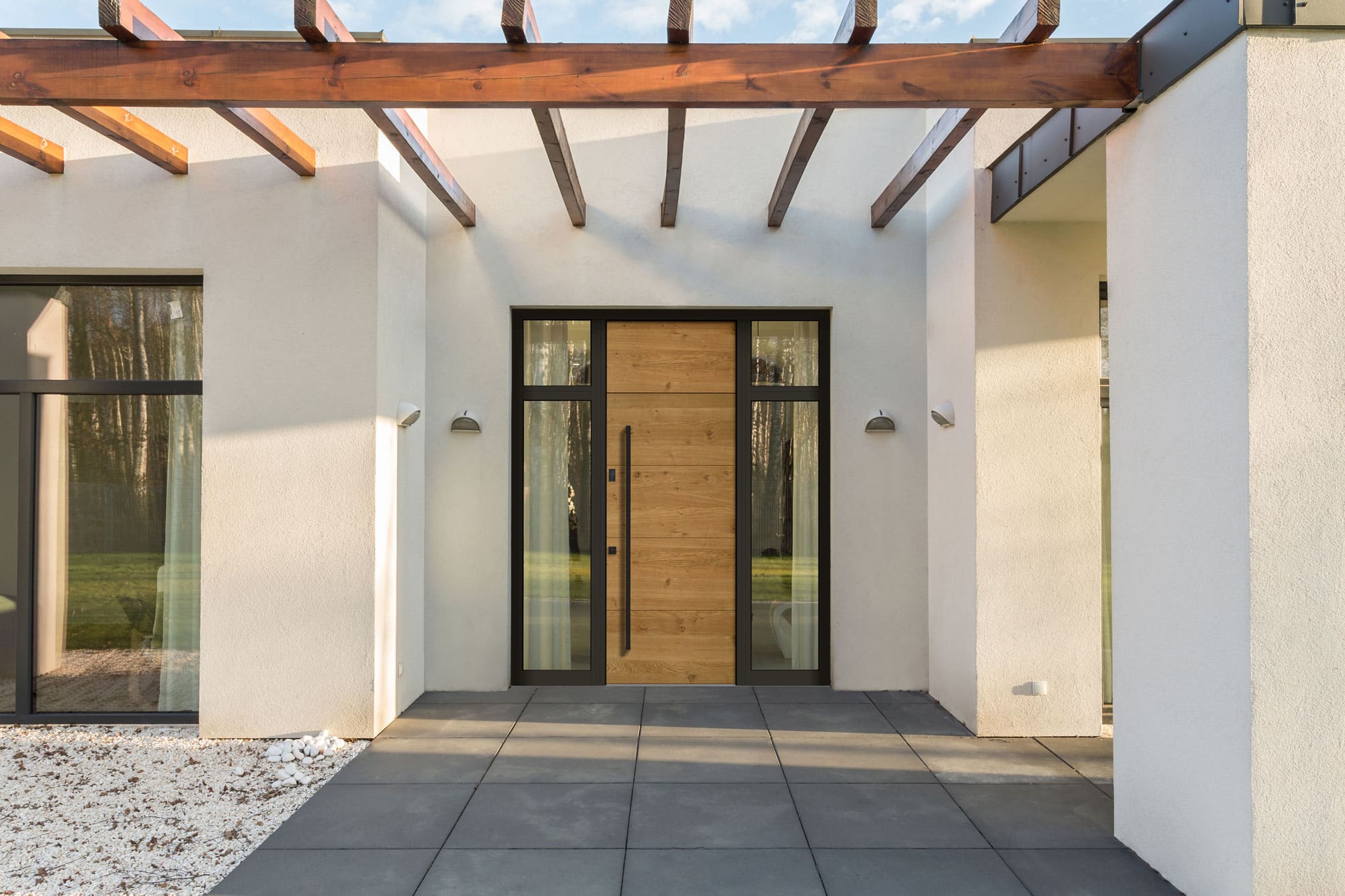 Haustür aus Holz und Aluminium mit Glasseitenteil unter einer Pergola