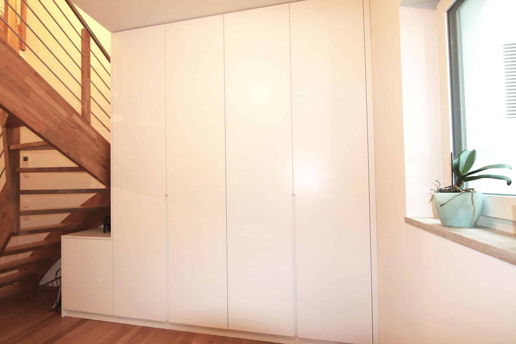 Weißer Einbauschrank unter der Holztreppe