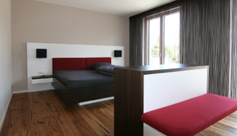 Schlafzimmer mit maßgefertigtem Bett und Raumteiler aus Holz