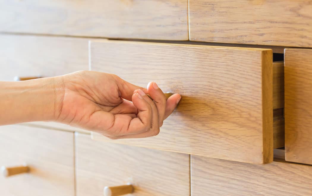 Hand öffnet eine Holzschublade