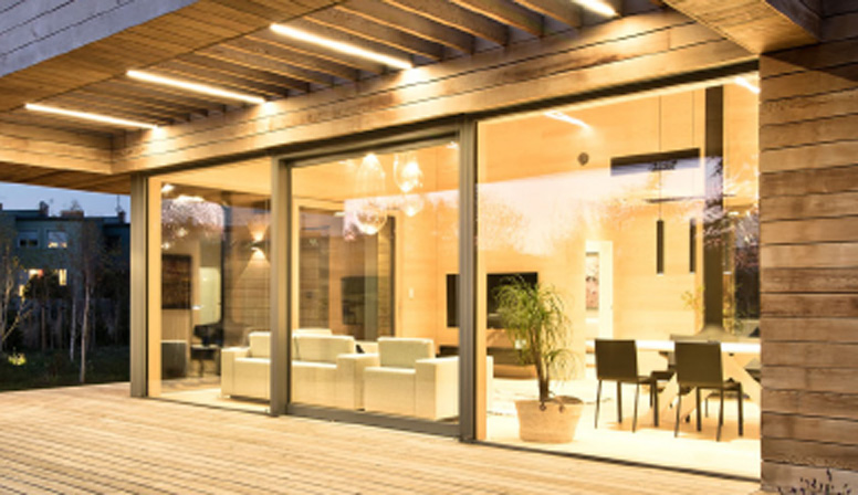 Wohnhaus mit großer Glasfront und Holzterrasse am Abend