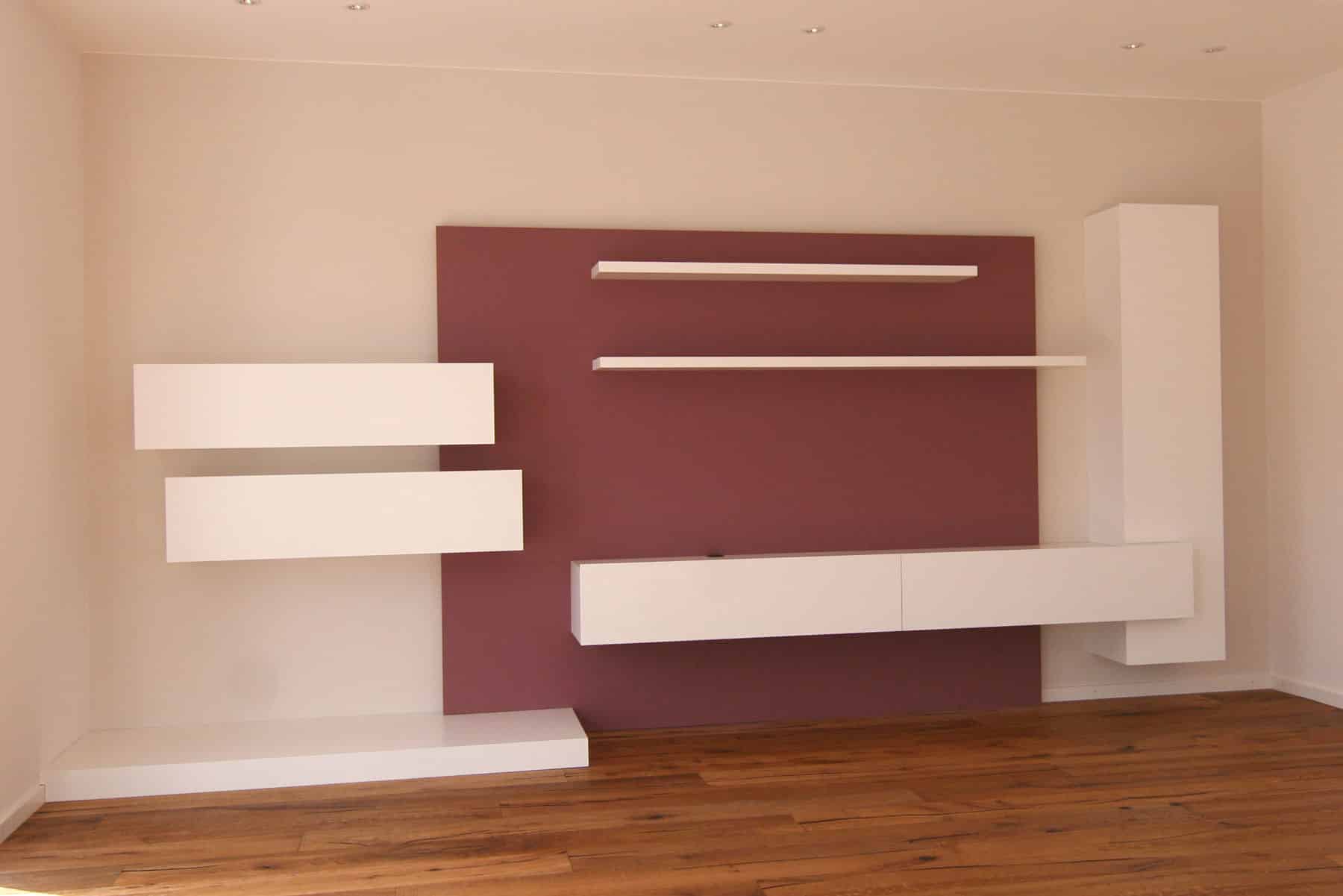 TV-Board mit weißen Hängeelementen an farbiger Wand