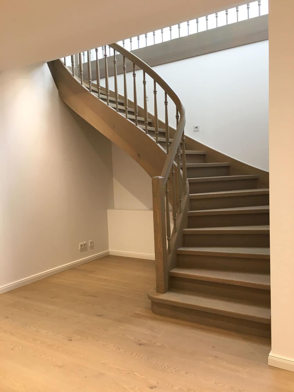 Geschwungene Echtholztreppe mit Holzgeländer