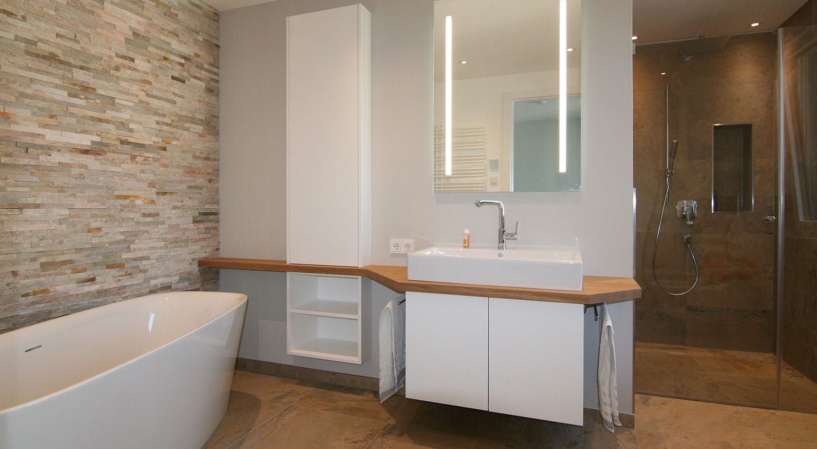 Badezimmer mit Waschtisch nach Maß, Hochschrank und freistehender Badewanne